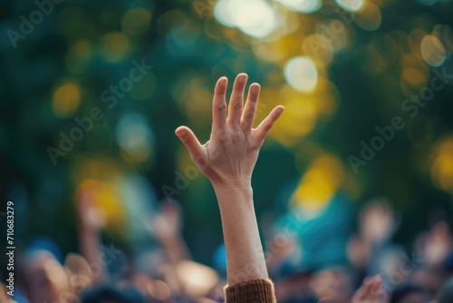 Raised hand with blurred crowd at outdoor concert