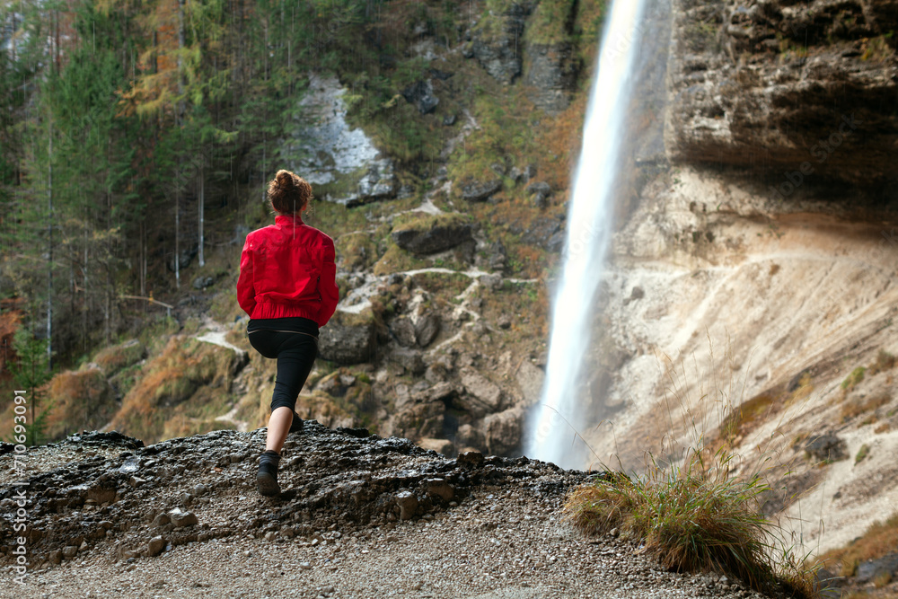 Adult Woman Stretching Exercises in Front of a Magnificent Big Waterfall