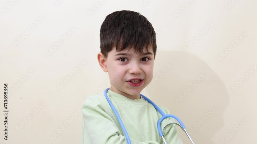 happy kid is playing with stethoscope sitting on bed. child preschooler boy isolated on wall backdrop.cute child is smiling,pediatrician doctor concept.healthy baby happy kid is playing with stethoscope sitting on bed. child preschooler boy isolated on wall backdrop.cute child is smiling,pediatrician doctor concept.healthy baby