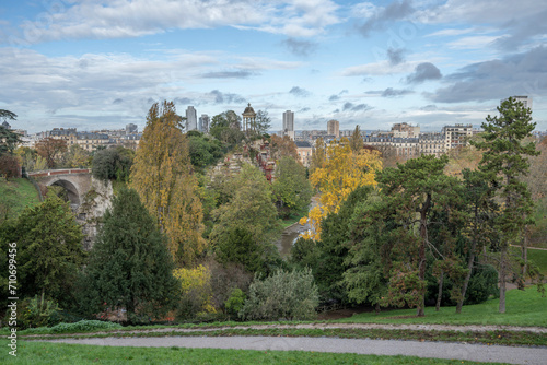 Paris, France - 11 11 2023: Park des Buttes Chaumont. View the central part of the park with footbridge, belvedere island, Temple of the Sibyl and the lake under construction due to renovation.