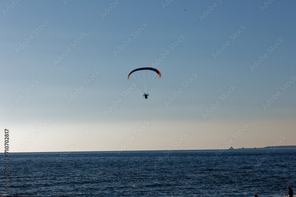 Motorized paraglider flying against the blue sky with clouds, outdoor activity, extreme sports, extreme sports, paraglider flying in the sun in the sky. The sport of paragliding Motorized paraglider flying against the blue sky with clouds, outdoor activity, extreme sports, extreme sports, paraglider flying in the sun in the sky. The sport of paragliding