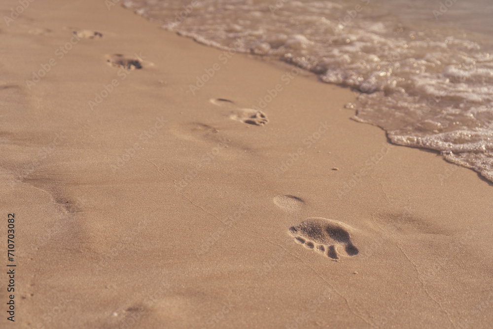 barefoot marks on the sand next to the water at a beach barefoot marks on the sand next to the water at a beach