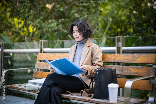 Woman sitting on park bench reading documents