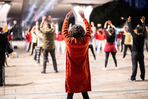 Middle-aged and elderly people dancing square dance under the city overpass at night