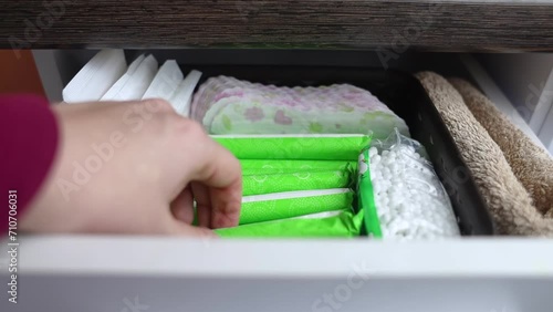 Sanitary napkin, tampon and cotton plant flower. Women hands pull out drawer containing hygiene products to help with menstruation. Cotton flower symbolizes absence of plastic. Made from eco materials photo