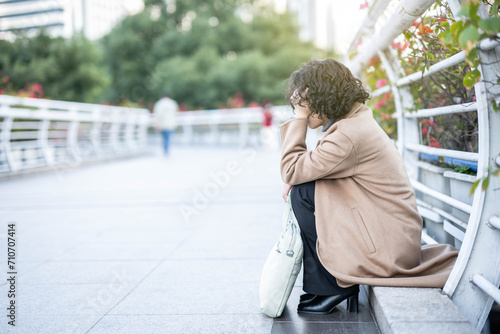 Middle-aged woman sitting on the ground holding her head photo