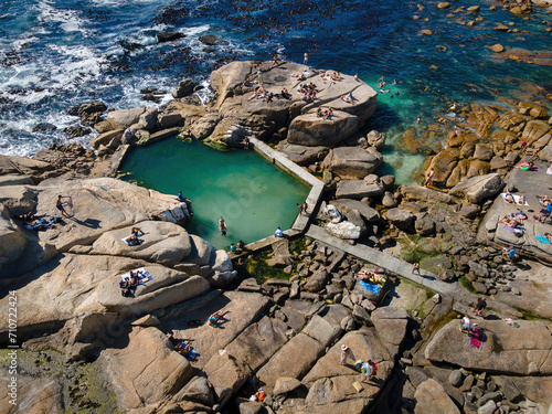 Aerial view of swimmers and beach goers at Saunder’s Rock tidal pool in summer in Bantry Bay, Atlantic Seaboard, Cape Town, South Africa.