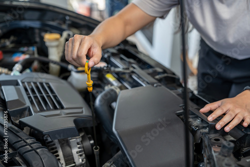 A young woman checking the car engine oil by herself