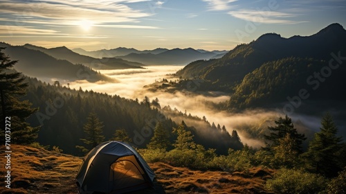 a tent pitched up on top of a hill with a view of a valley and mountains in the distance with fog in the air.