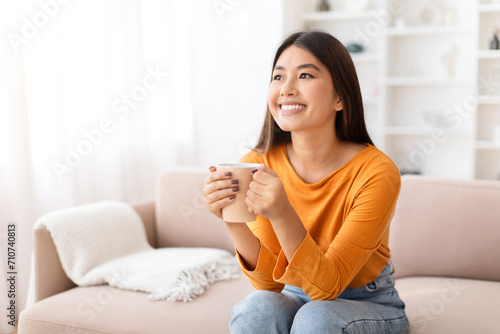 Portrait of happy young asian woman drinking coffee at home