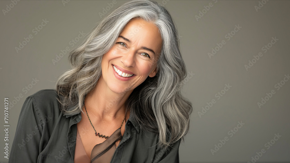 a clean studio portrait of a middle-aged caucasian woman with blond silver hair in white t-shirt looking into the camera smiling, grey background. a clean studio portrait of a middle-aged caucasian woman with blond silver hair in white t-shirt looking into the camera smiling, grey background.