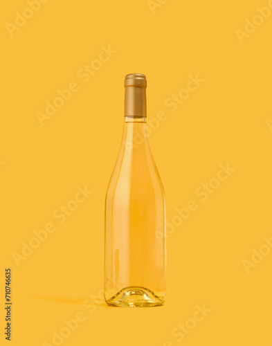 A bottle of white wine on a yellow background. Luxury alcohol vacation.