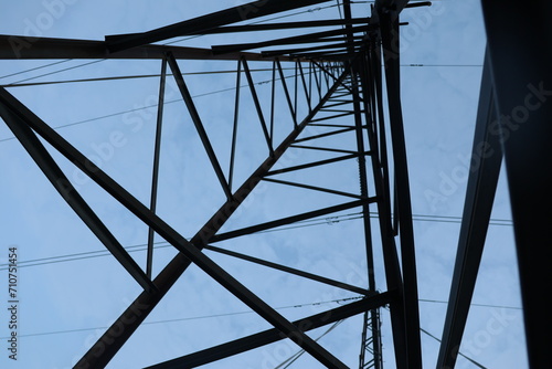 Low angle shot of a high-voltage power line under a bright blue sky