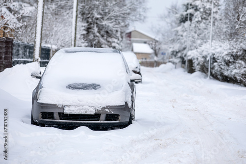 Snow-covered car in the street covered with a thick layer of snow on a winter day © STOATPHOTO