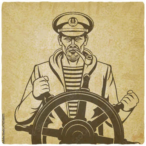 Man with a smoking pipe in a captain's cap at the helm of the ship