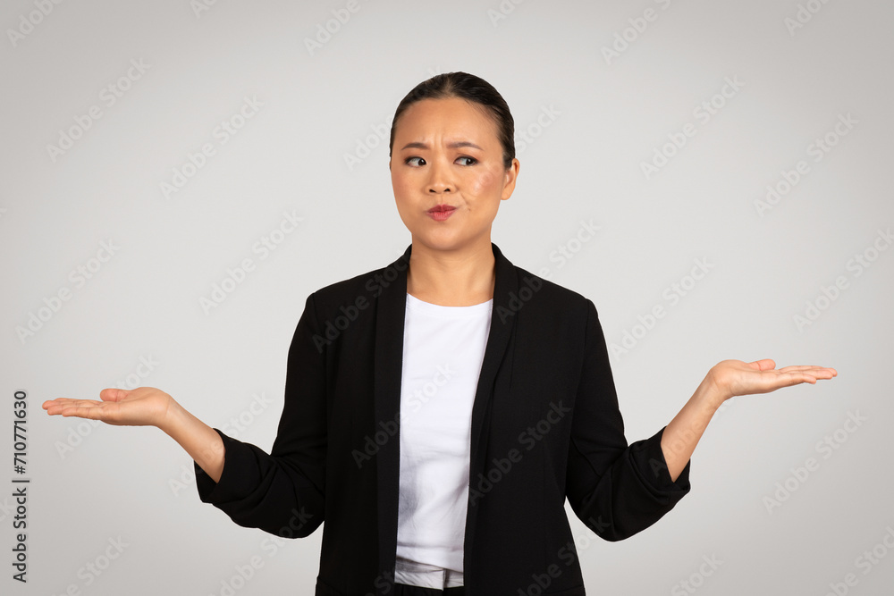 Perplexed Asian businesswoman with palms up in a questioning gesture, showing uncertainty Perplexed Asian businesswoman with palms up in a questioning gesture, showing uncertainty