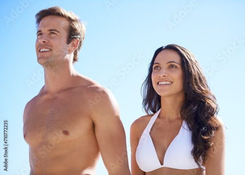 Smile, blue sky and couple on beach for travel, vacation or honeymoon in summer. Nature, vision or view with happy young man and woman outdoor for coastal holiday, bikini or getaway adventure