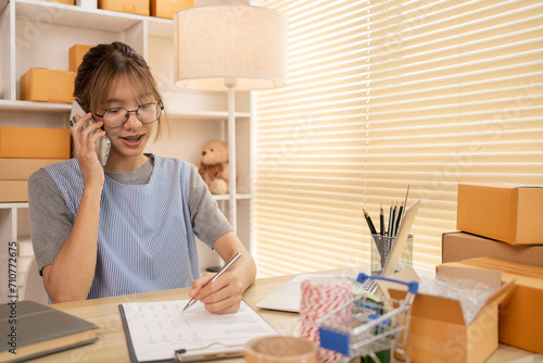 Sell products online, Young woman Multitasking: take orders from customers who call by phone, Young woman who has a lot of work and is very busy with work, Freelance working. © Puwasit Inyavileart