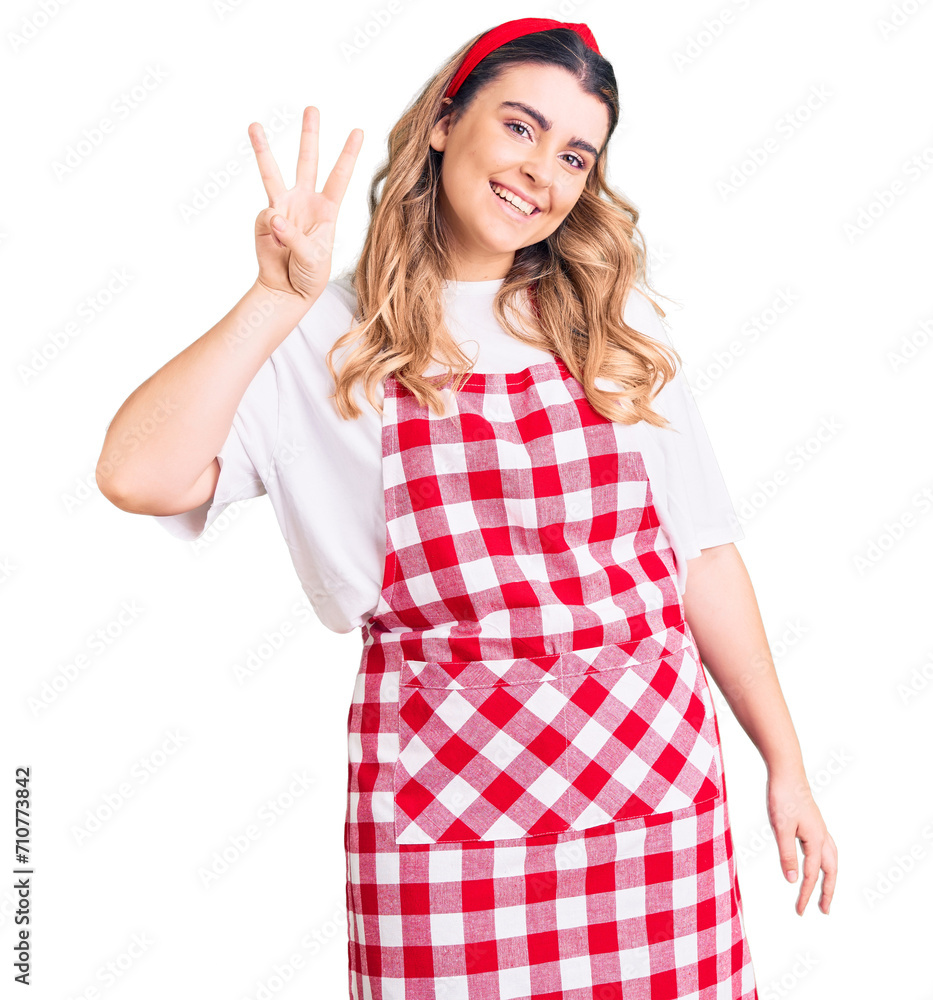 Young caucasian woman wearing apron showing and pointing up with fingers number three while smiling confident and happy. Young caucasian woman wearing apron showing and pointing up with fingers number three while smiling confident and happy.