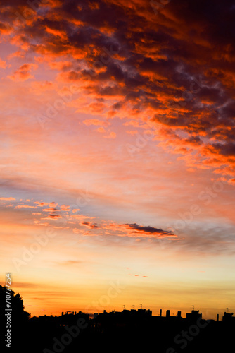  Intense orange clouds at twilight over urban silhouette.