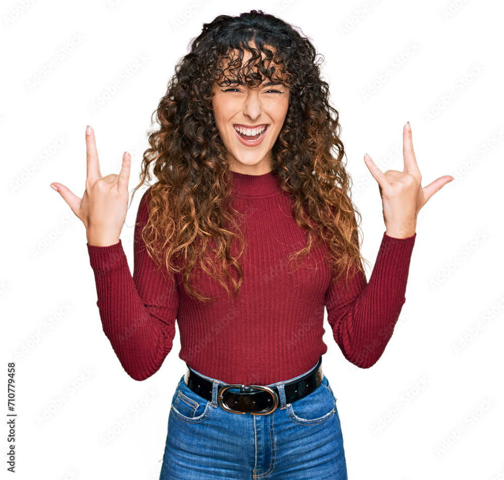 Young hispanic girl wearing casual clothes shouting with crazy expression doing rock symbol with hands up. music star. heavy concept. Young hispanic girl wearing casual clothes shouting with crazy expression doing rock symbol with hands up. music star. heavy concept.