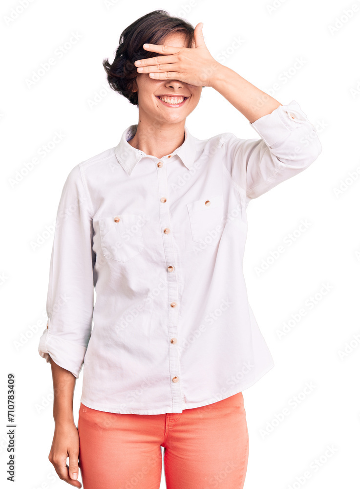 Beautiful young woman with short hair wearing elegant white shirt smiling and laughing with hand on face covering eyes for surprise. blind concept. Beautiful young woman with short hair wearing elegant white shirt smiling and laughing with hand on face covering eyes for surprise. blind concept.