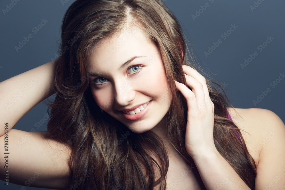 Obraz premium Woman, hair and natural beauty in portrait with cosmetics, hairstyle and grooming on grey background. Happy, skin with wellness and dermatology for skincare, growth and haircare shine in studio