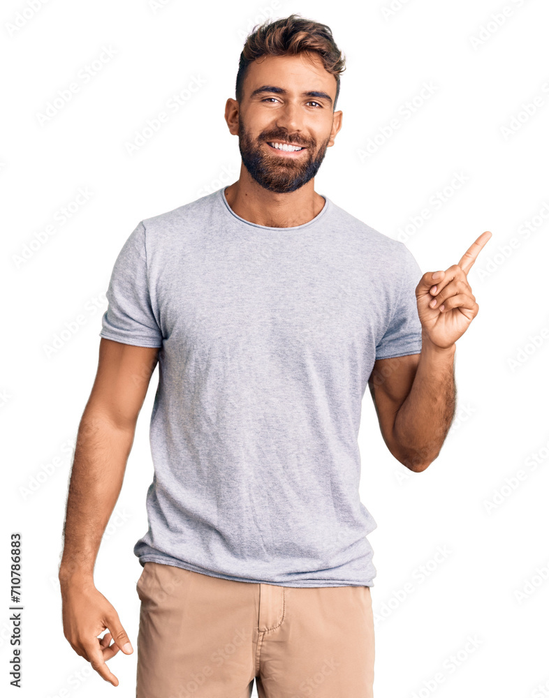 Young hispanic man wearing casual clothes with a big smile on face, pointing with hand finger to the side looking at the camera. Young hispanic man wearing casual clothes with a big smile on face, pointing with hand finger to the side looking at the camera.