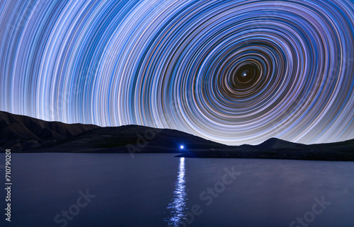 Beautiful night landscape, star trailers on the lake. Time-lapse, long exposure.