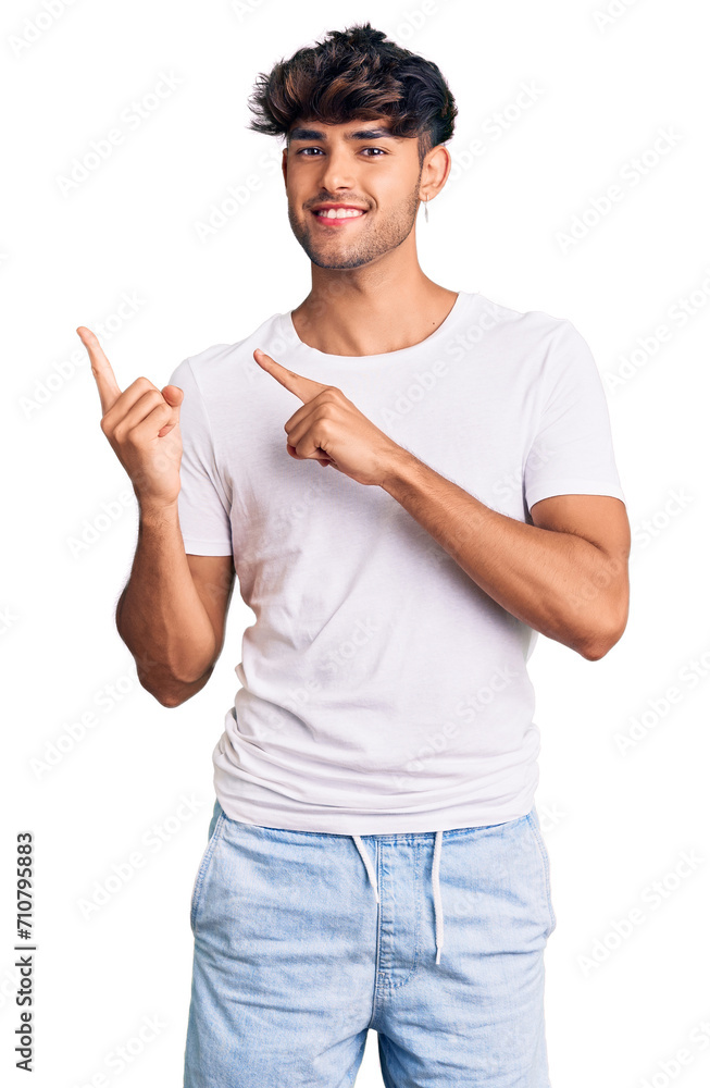 Young hispanic man wearing casual clothes smiling and looking at the camera pointing with two hands and fingers to the side. Young hispanic man wearing casual clothes smiling and looking at the camera pointing with two hands and fingers to the side.