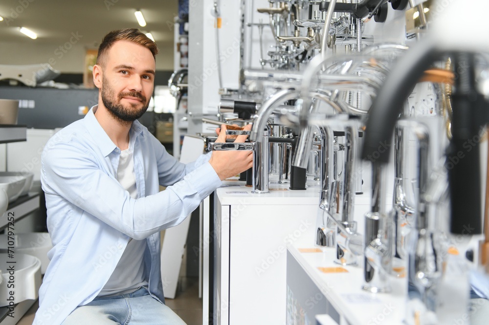 Fototapeta premium A large selection of water faucets. Man chooses a products in a sanitary ware store