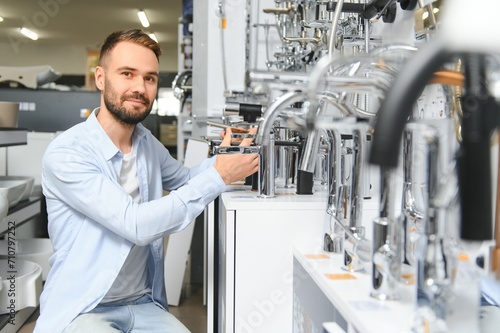 A large selection of water faucets. Man chooses a products in a sanitary ware store