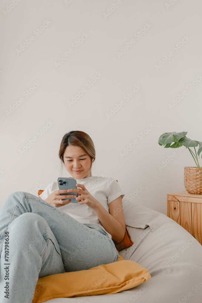 Asian woman sitting on beanbag and using smartphone. Asian woman sitting on beanbag and using smartphone.