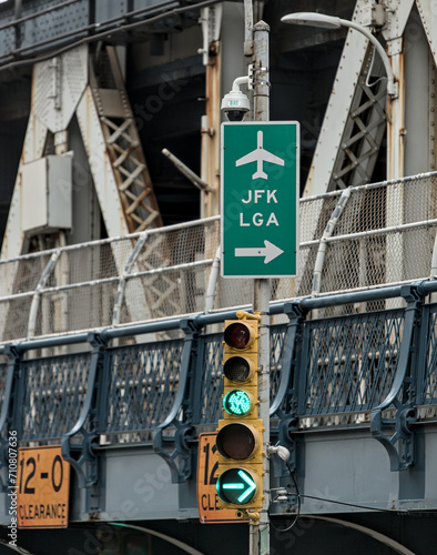 JFK and LGA sign on traffic light with manhattan bridge in the background (close up of directional signs to john f kennedy, laguardia airport) green light signal photo