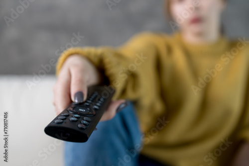 shallow depth of field remote control in a woman's hand, watching TV at home in a cozy place photo