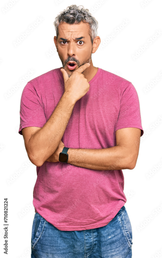 Middle age grey-haired man wearing casual clothes looking fascinated with disbelief, surprise and amazed expression with hands on chin Middle age grey-haired man wearing casual clothes looking fascinated with disbelief, surprise and amazed expression with hands on chin