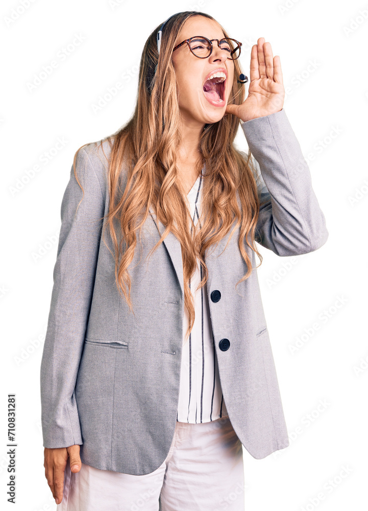 Young beautiful blonde woman wearing call center agent headset shouting and screaming loud to side with hand on mouth. communication concept. Young beautiful blonde woman wearing call center agent headset shouting and screaming loud to side with hand on mouth. communication concept.