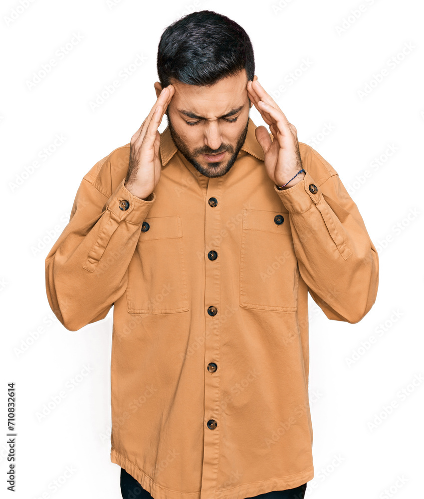 Young hispanic man wearing casual clothes with hand on head for pain in head because stress. suffering migraine. Young hispanic man wearing casual clothes with hand on head for pain in head because stress. suffering migraine.