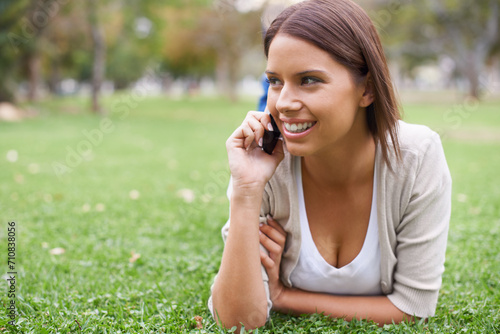 Woman, phone call and relax on grass talking for communication, good news or gossip. Female person, smile and digital device in forest for holiday rest or laughing conversation, vacation or nature