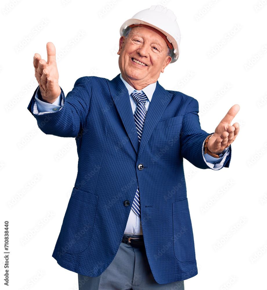 Senior handsome grey-haired man wearing suit and architect hardhat looking at the camera smiling with open arms for hug. cheerful expression embracing happiness. Senior handsome grey-haired man wearing suit and architect hardhat looking at the camera smiling with open arms for hug. cheerful expression embracing happiness.