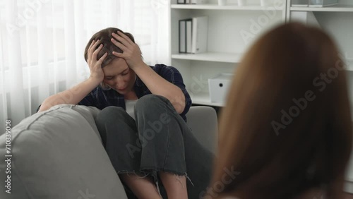 Sad PTSD woman patient in therapy for mental health with psychologist, depression or grief after life failure. Frustrated trauma young woman talking to prim psychologist about emotion in clinic photo