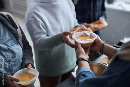 Closeup of unrecognizable volunteer serving hot soup and meals to people in need at refugee help center, copy space