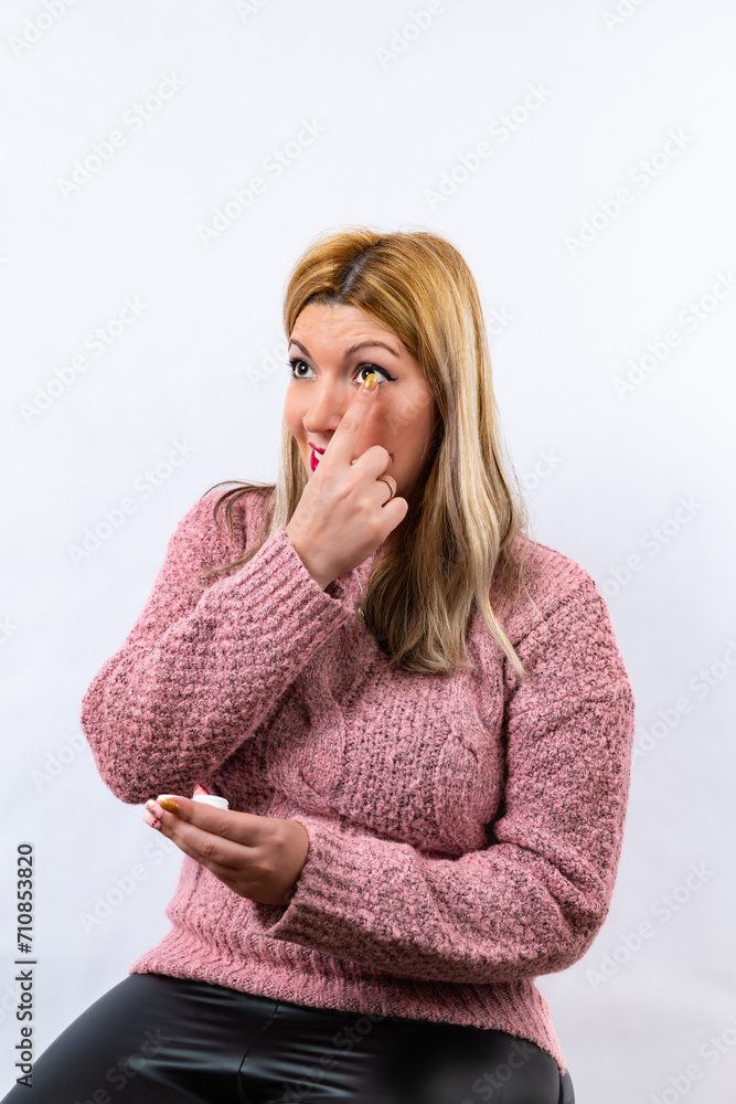 Blonde girl putting on contact lenses Blonde girl putting on contact lenses