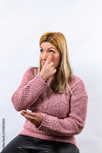 Blonde girl putting on contact lenses