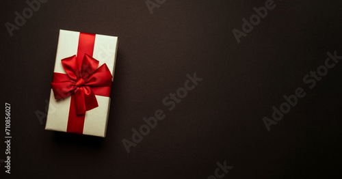Light yellow gift box with red bow on black background