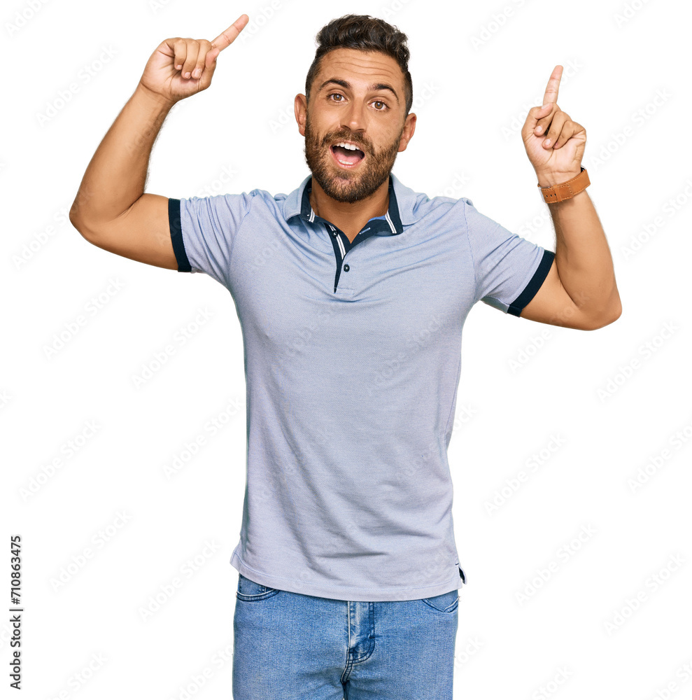 Handsome man with beard wearing casual clothes smiling amazed and surprised and pointing up with fingers and raised arms. Handsome man with beard wearing casual clothes smiling amazed and surprised and pointing up with fingers and raised arms.