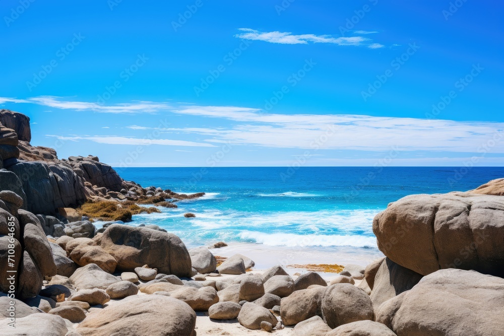 A scenic rocky beach with crystal blue water and various sized rocks scattered along the shore, Big rocks on the ocean landscape beach view with a blue sky, AI Generated