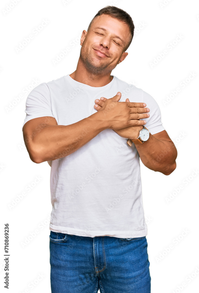 Handsome muscle man wearing casual white tshirt smiling with hands on chest with closed eyes and grateful gesture on face. health concept. Handsome muscle man wearing casual white tshirt smiling with hands on chest with closed eyes and grateful gesture on face. health concept.