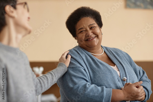 Portrait of senior African American woman smiling in group therapy session with people supporting her, copy space
