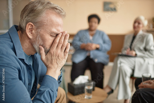 Side view portrait of crying senior man in group therapy session struggling with mental health issues, copy space photo
